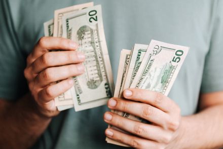 Crop man counting dollar banknotes